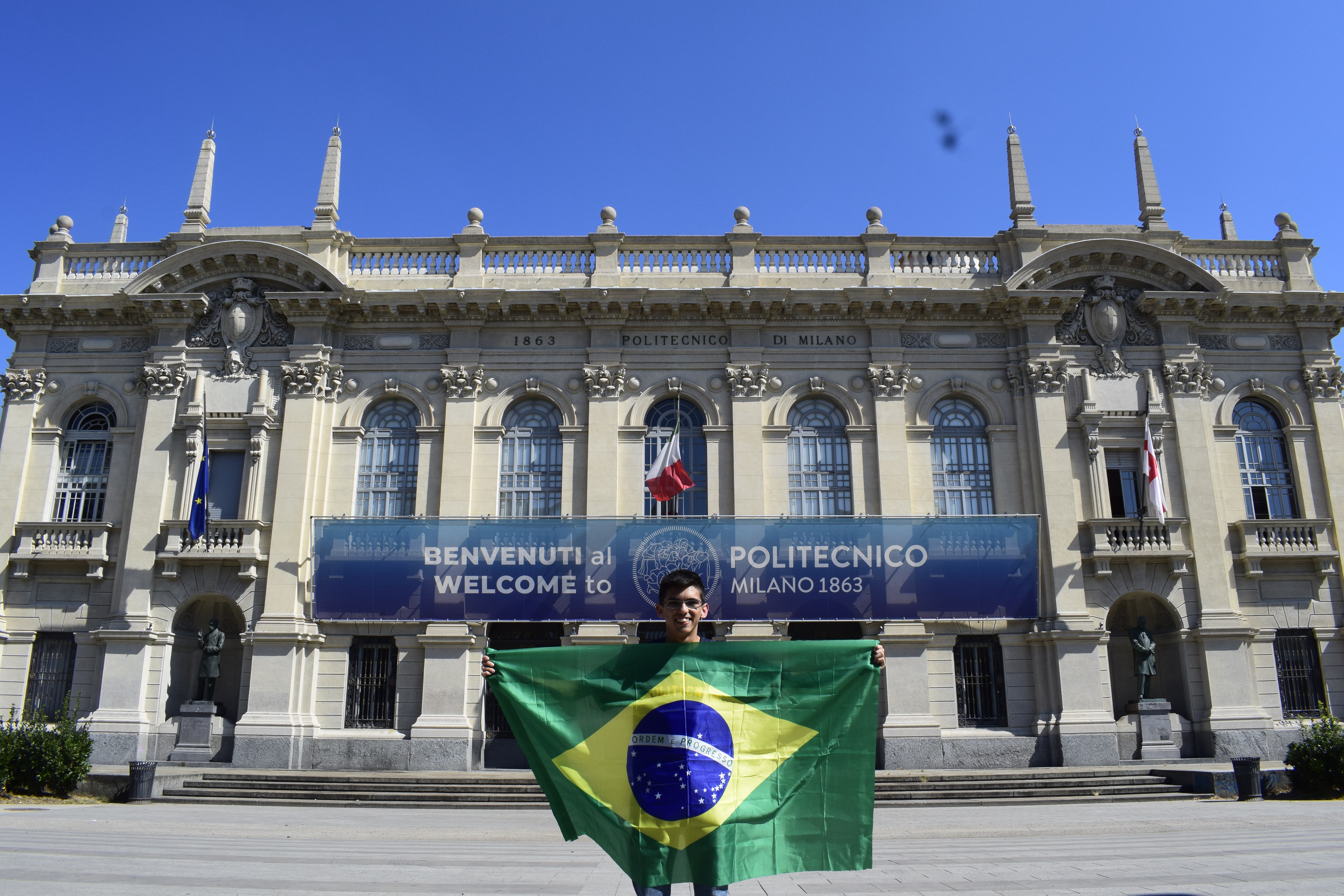 in front of the Leonardo campus of Politecnico, proudly holding up a Brazilian flag